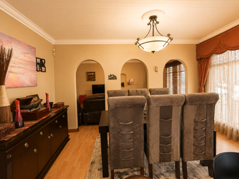 A formal dining room featuring classic archways, crown molding, and a central chandelier, providing a warm and inviting space for meals.