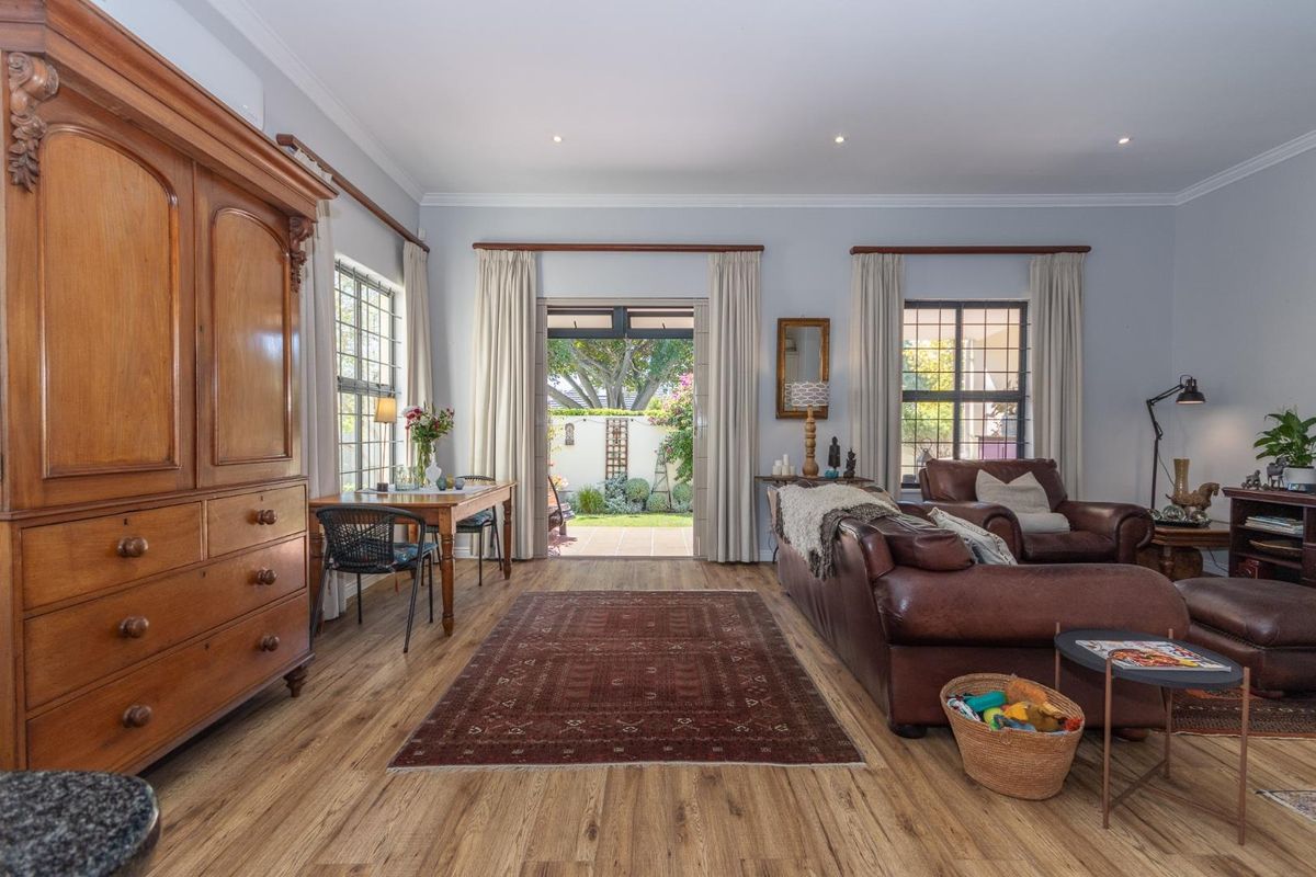 Spacious living room featuring laminate flooring, recessed lighting, and large windows, with direct access to a private rear patio area.