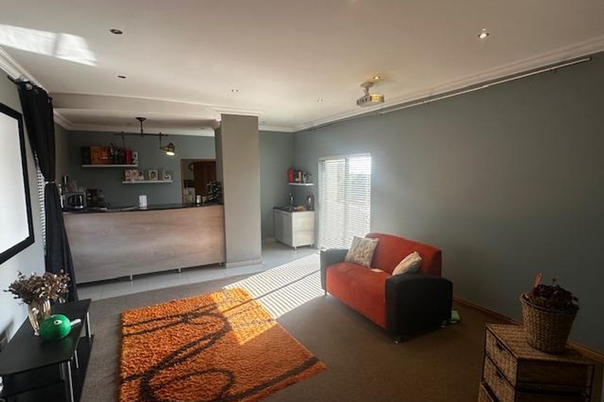 A spacious living area featuring a built-in bar counter, recessed ceiling lighting, and large windows allowing for natural light.