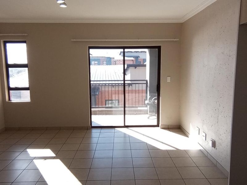 An empty living room featuring tiled flooring, coving, and a sliding glass door providing access to a balcony.