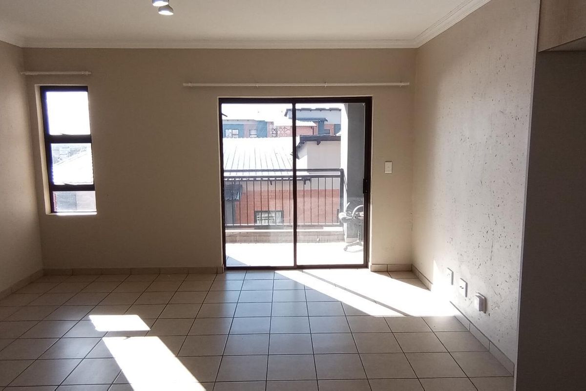 An empty living room featuring tiled flooring, coving, and a sliding glass door providing access to a balcony.