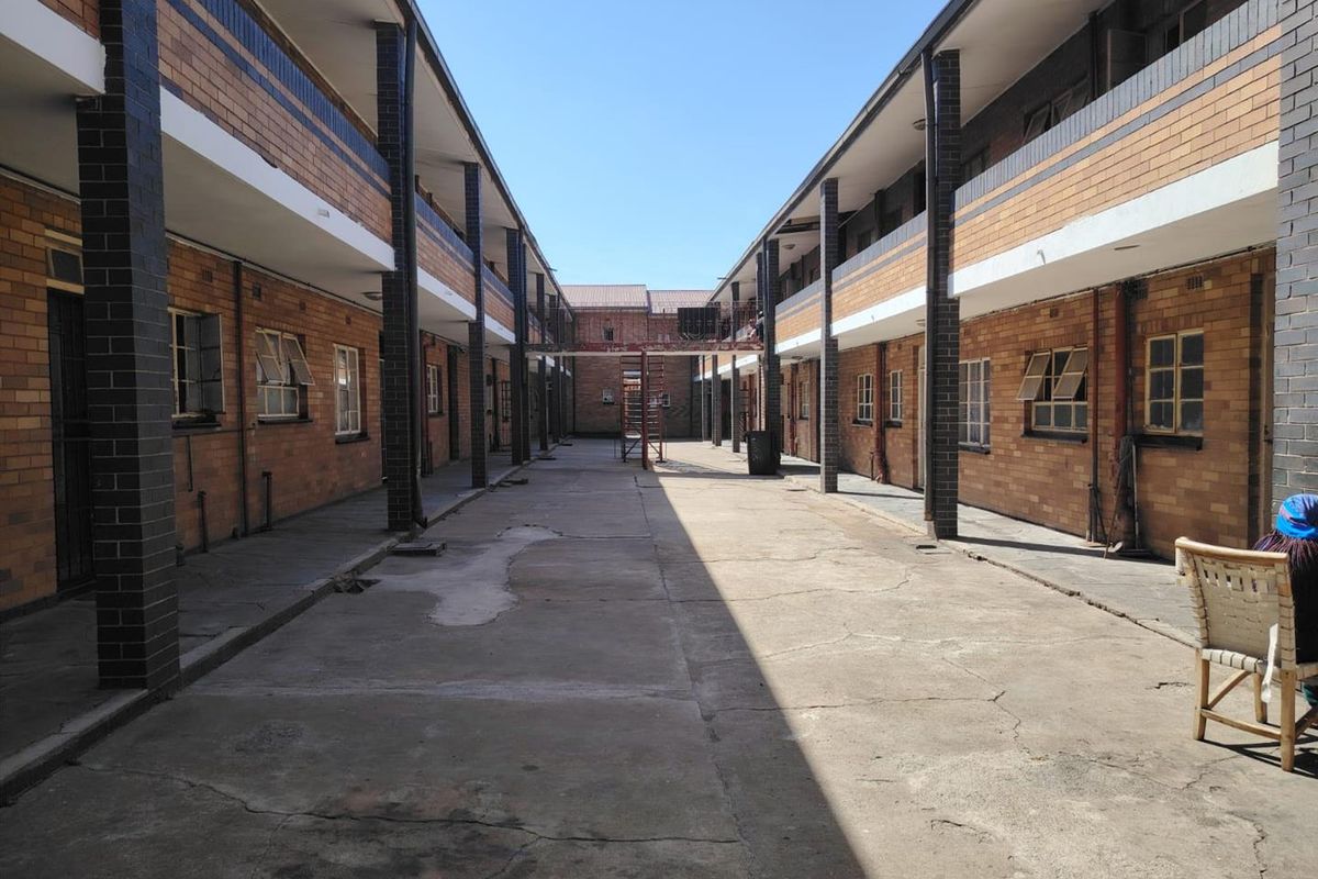 An exterior view of an apartment complex courtyard featuring brick facades, covered walkways, and a central concrete paved area.