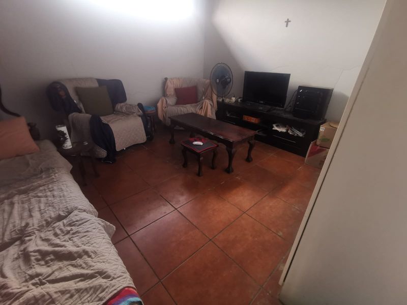 A living room featuring terracotta floor tiles and visible wall cracks, offering a functional space ready for cosmetic updates and modernization.