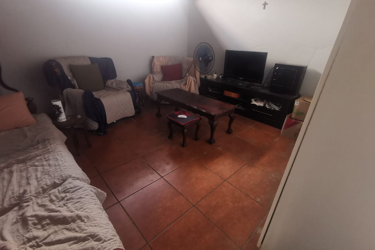 A living room featuring terracotta floor tiles and visible wall cracks, offering a functional space ready for cosmetic updates and modernization.