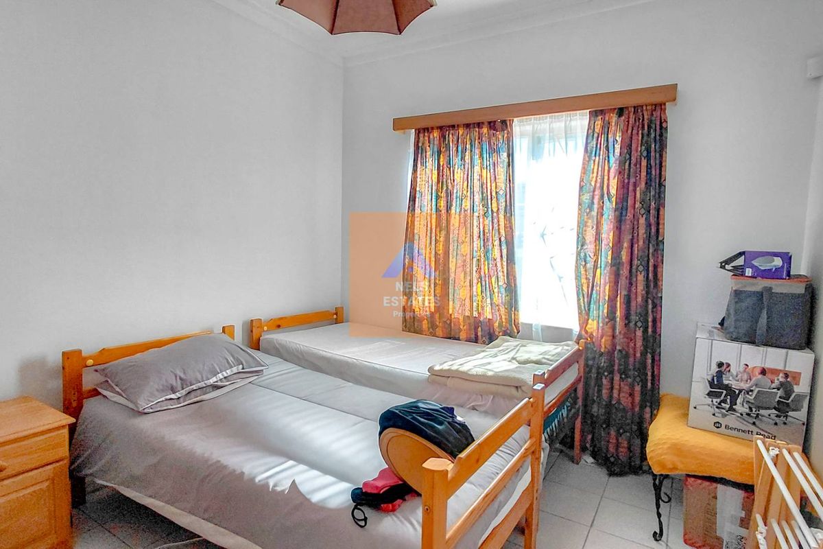 A functional bedroom featuring tiled flooring and a window with a curtain rod, offering a neutral space ready for personalization.