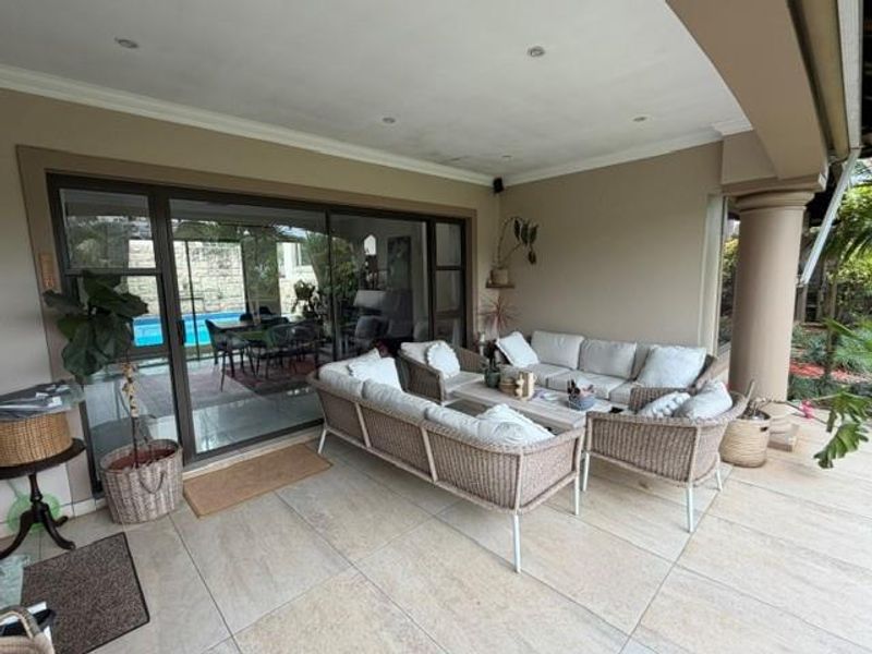 A spacious covered patio featuring tiled flooring, recessed lighting, and large sliding glass doors that provide seamless access to the interior living area.