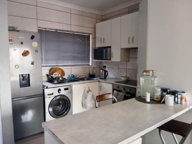 Compact kitchen featuring built-in cabinetry, integrated oven and cooktop, tiled backsplash, and a functional breakfast bar area.