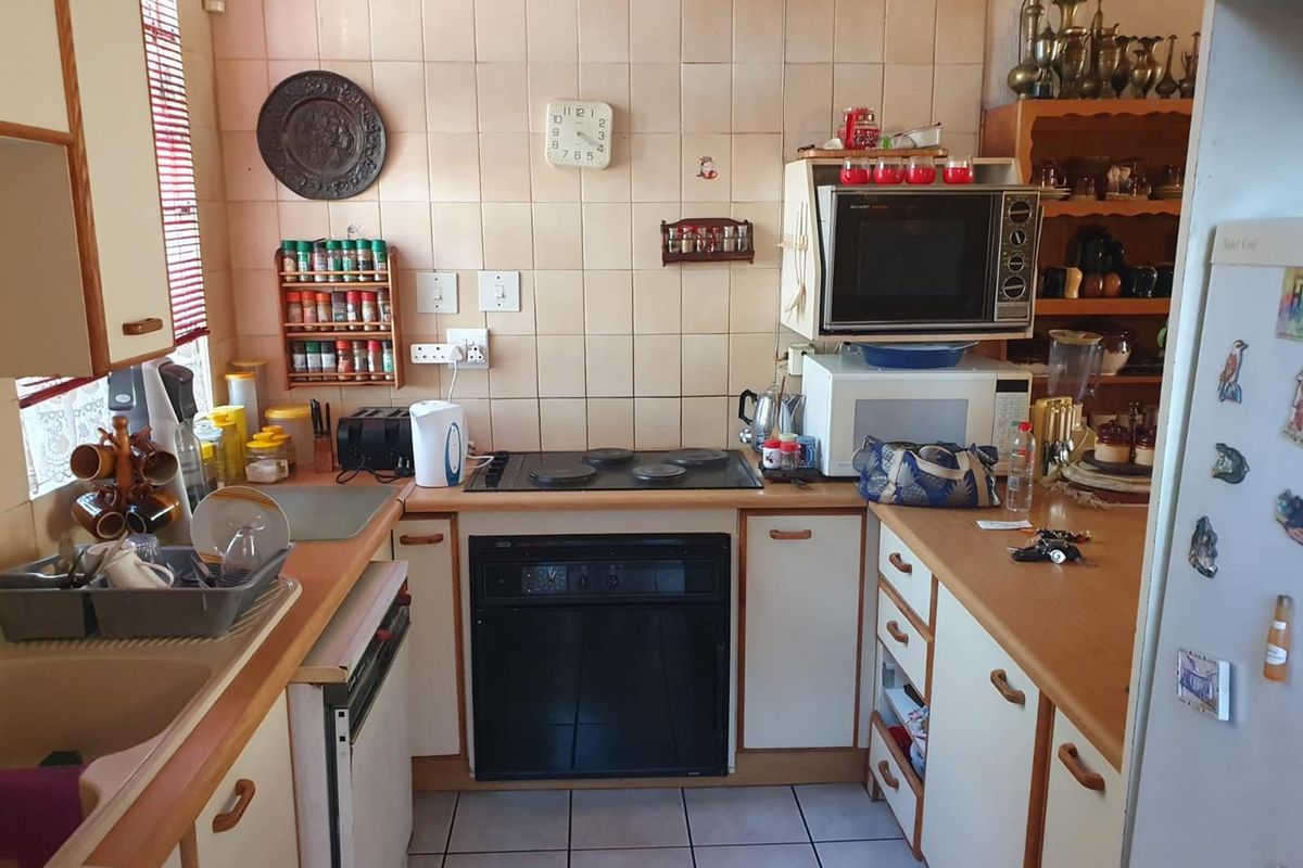 A compact kitchen featuring built-in cabinetry, a fitted electric hob and oven, and tiled splashbacks, offering a functional layout for renovation.