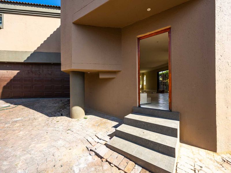 Front exterior view showing a paved driveway, sectional garage door, and concrete entrance steps leading into the home.