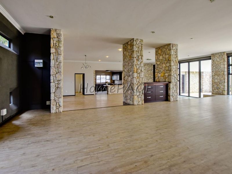 Spacious open-plan living area featuring striking stone-clad columns, modern laminate flooring, and large sliding glass doors that provide ample natural light.