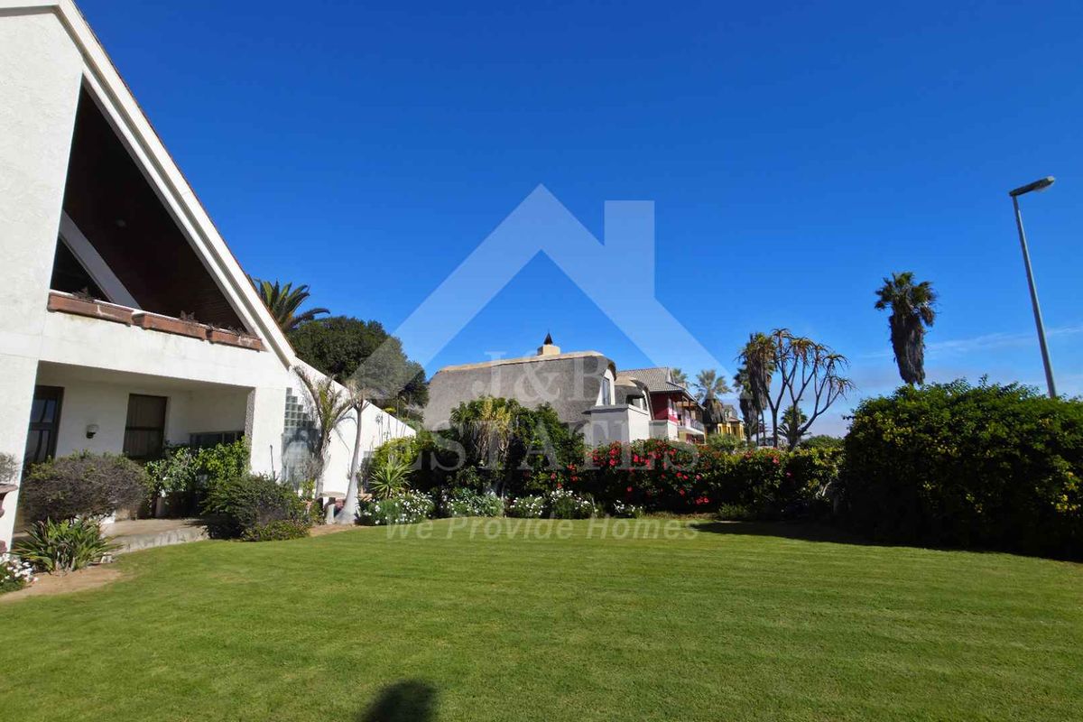 A spacious rear garden featuring a well-maintained lawn, mature landscaping, and a view of the property's rear elevation and surrounding neighbourhood.
