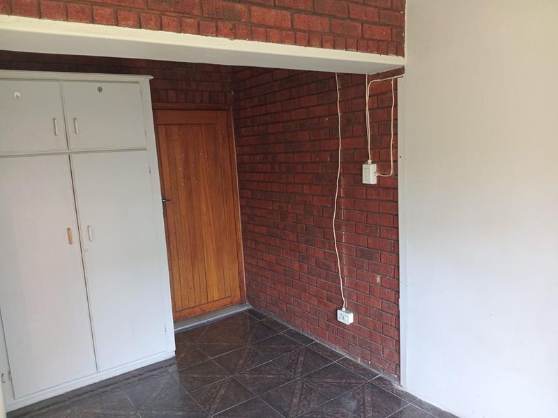 An entry area featuring exposed brick walls, tiled flooring, and built-in storage cupboards, requiring minor cosmetic updates and electrical tidying.