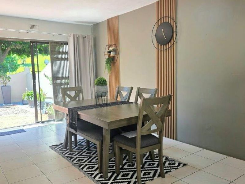 A bright dining area featuring modern timber wall slats, tiled flooring, and large sliding glass doors providing direct access to the outdoor patio.