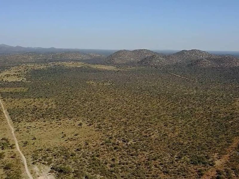 An expansive aerial view of the farm property, showcasing the vast natural landscape and a dirt access road winding through the terrain.