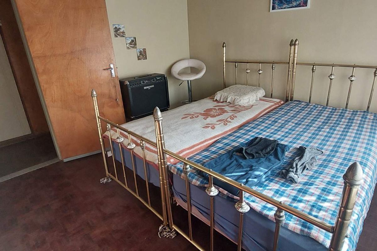 A bedroom featuring parquet flooring and a wooden door, currently furnished with twin beds.