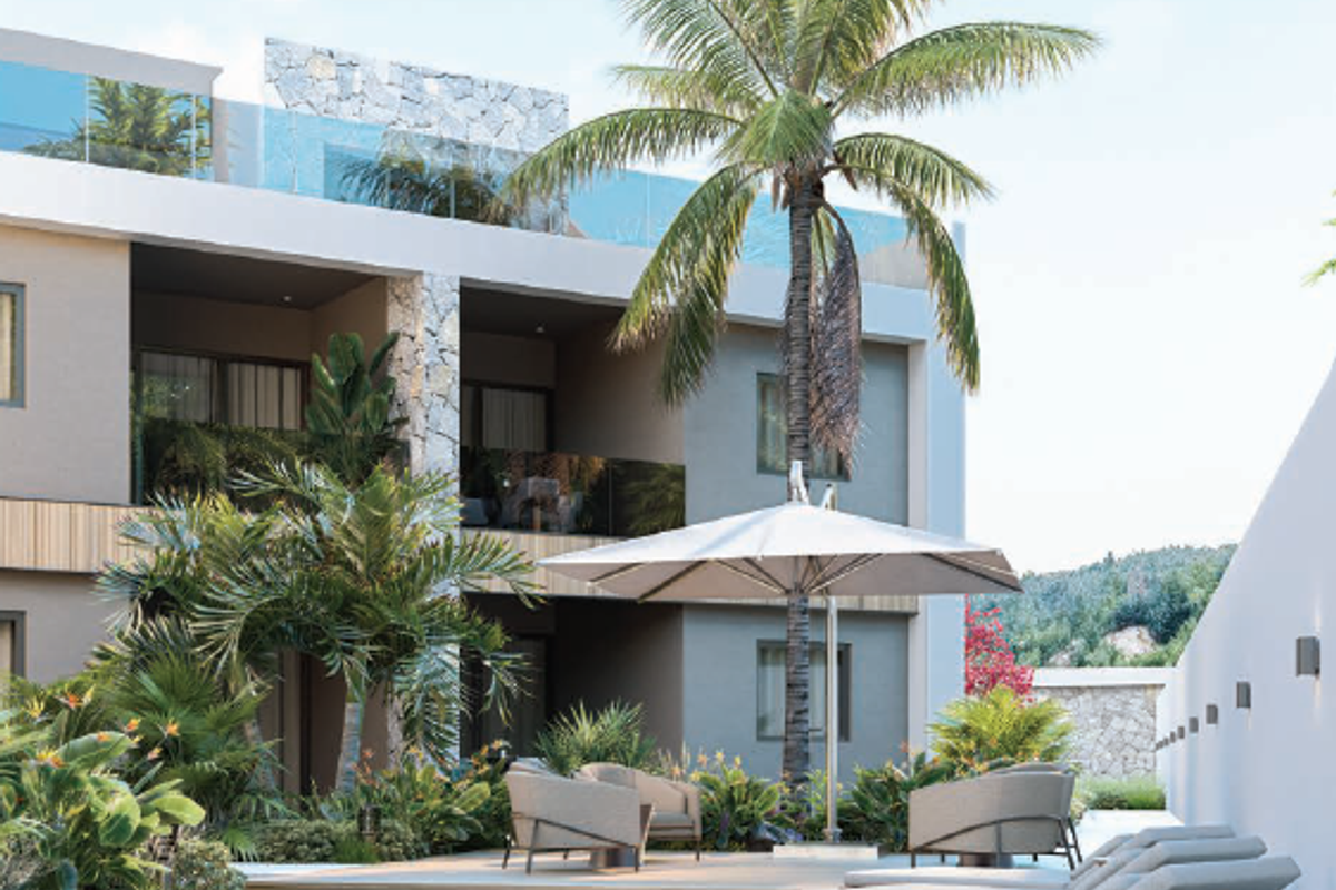 A modern apartment complex pool area featuring stone-clad architectural details, glass balustrades, and a well-maintained deck surrounded by lush tropical landscaping.