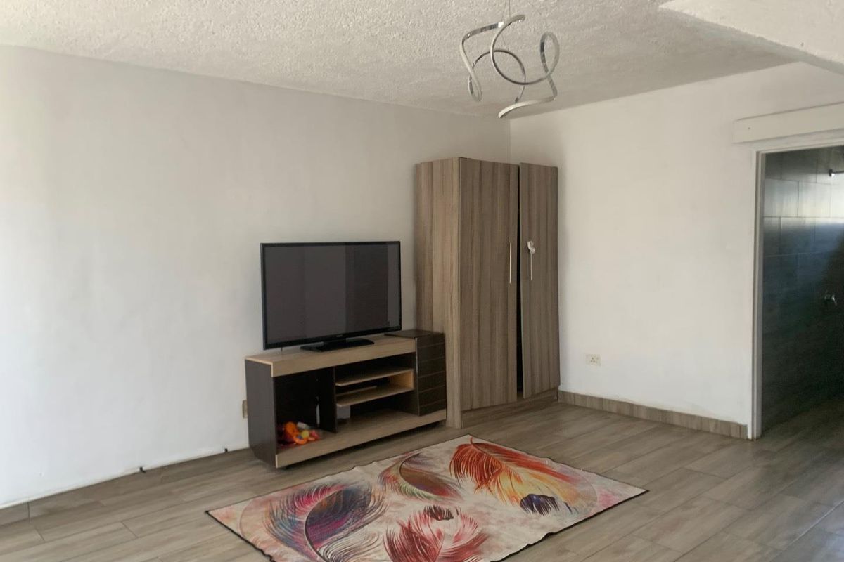 A bedroom featuring wood-look tile flooring, a textured ceiling, and a modern pendant light fixture.