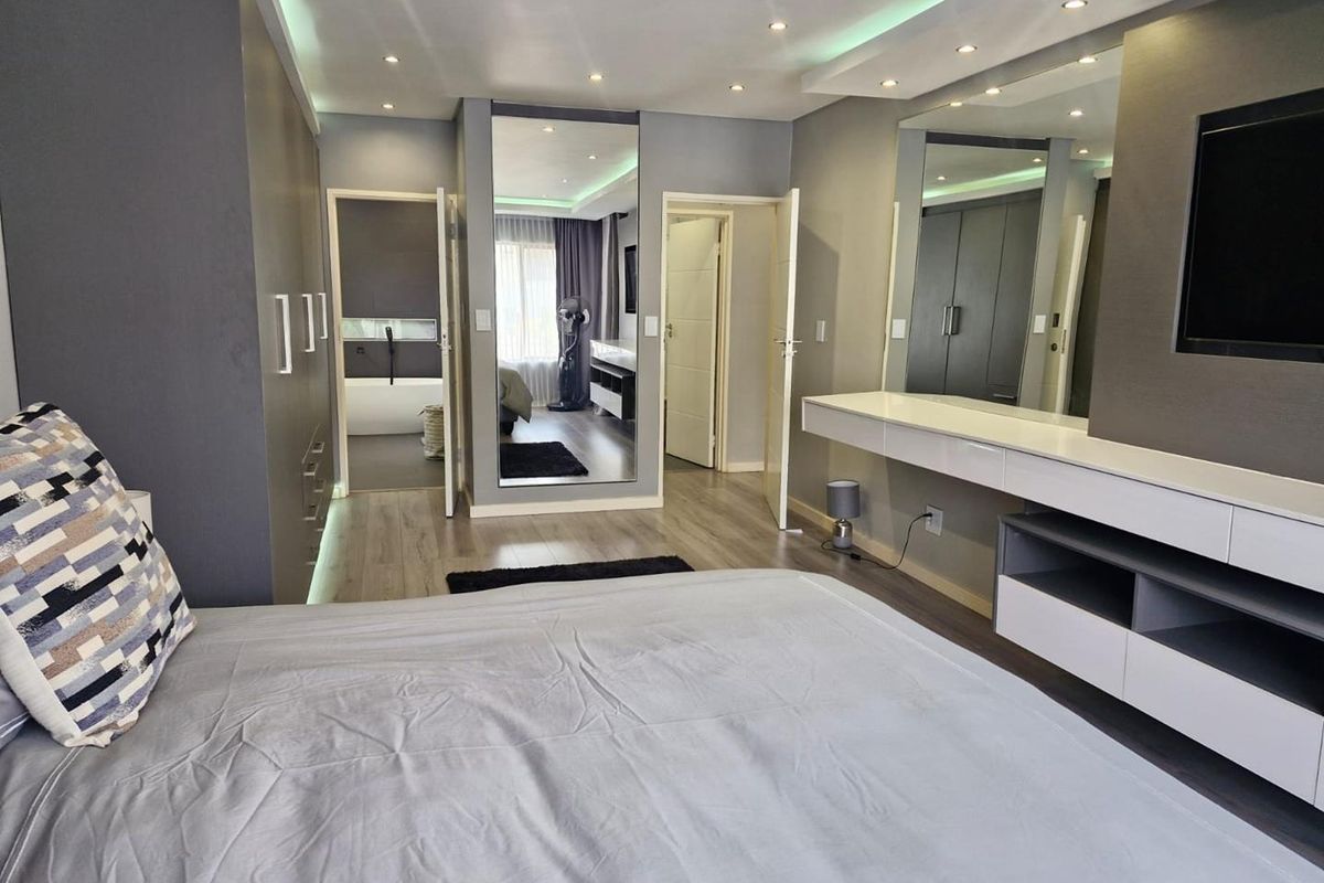 Modern bedroom featuring built-in cabinetry, recessed ceiling lighting, a floating vanity unit, and an en-suite bathroom with a soaking tub.