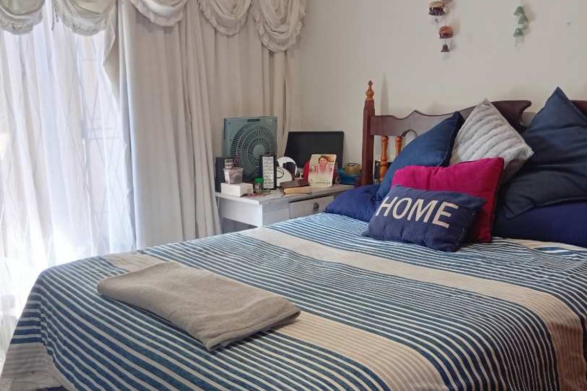 A bedroom featuring a sliding glass door with curtains, providing natural light and access to the exterior.