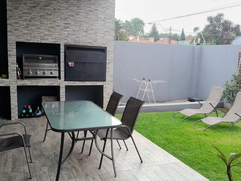 Covered patio area featuring a built-in braai, tiled flooring, and direct access to a private garden space.