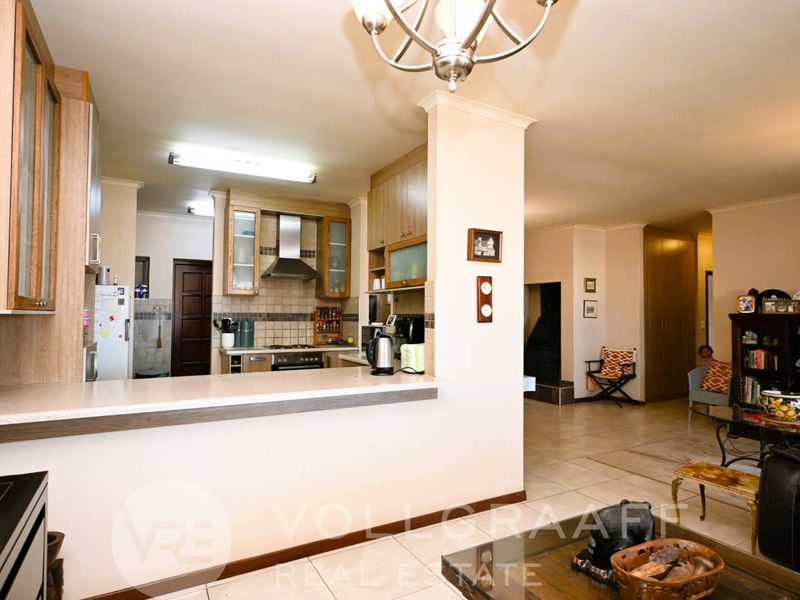 Open plan kitchen and living area featuring a breakfast bar, tiled flooring, and built-in cabinetry with integrated extractor fan.