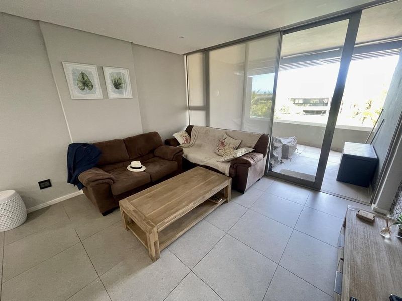 A bright living room featuring large sliding glass doors that provide access to an outdoor balcony area and ample natural light.