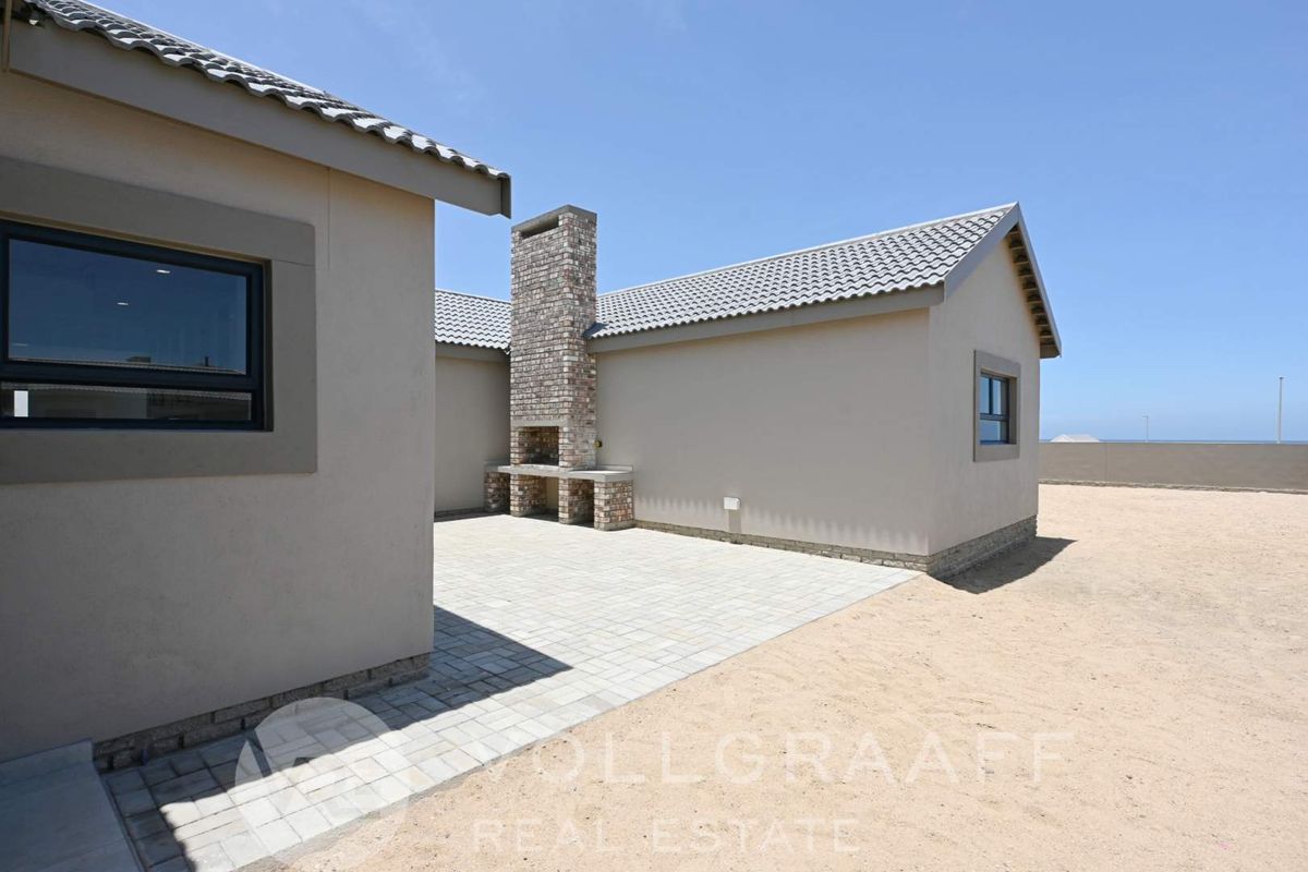 A paved rear patio area featuring a built-in brick braai fireplace, set against the exterior wall of the house.