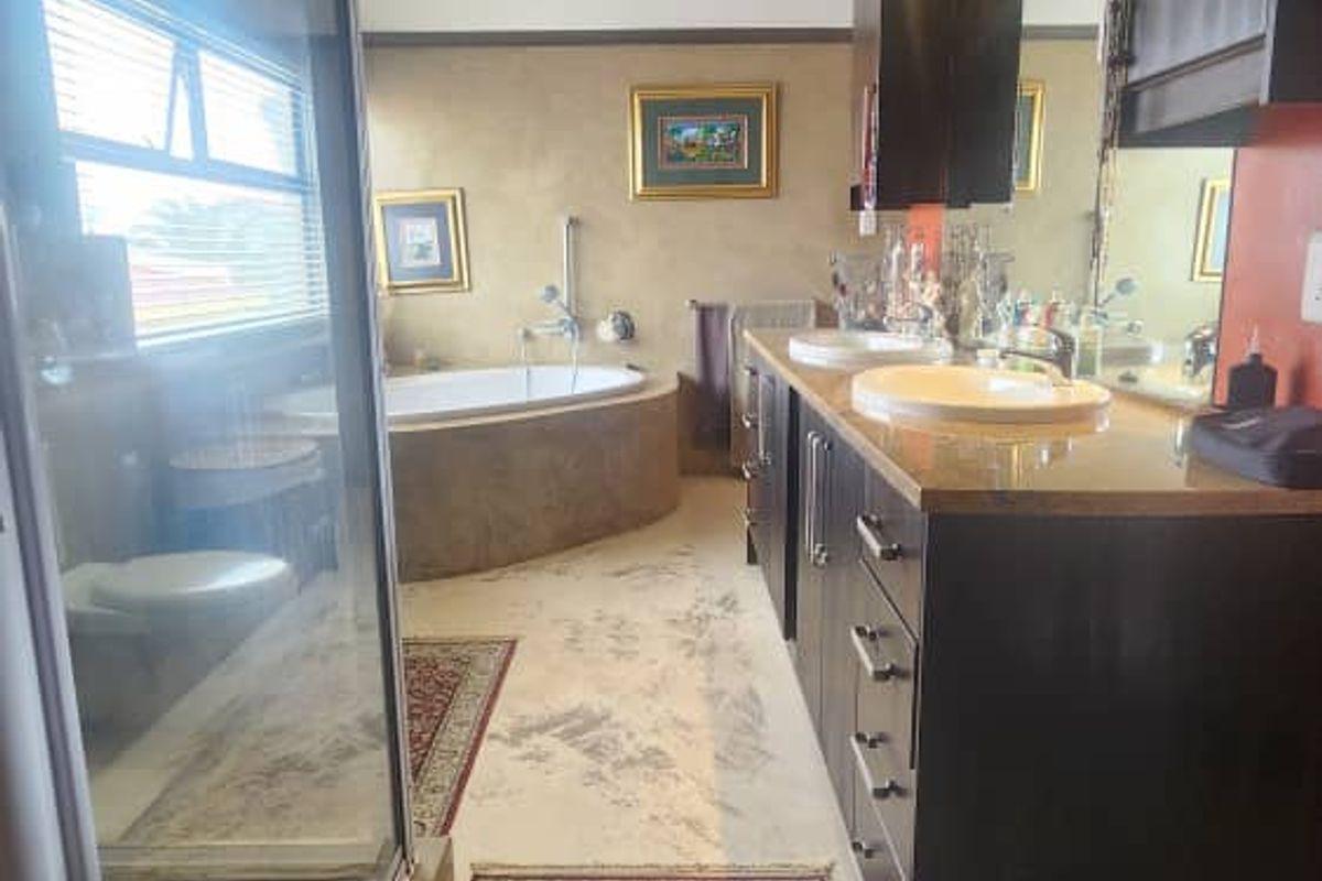 Spacious bathroom featuring a double vanity with dark cabinetry, a built-in soaking tub, and a separate glass-enclosed shower area.