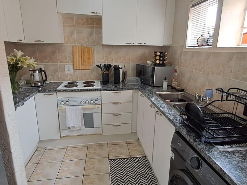 Functional kitchen featuring white cabinetry, granite countertops, tiled backsplash, and integrated electric cooking appliances with ample storage space.