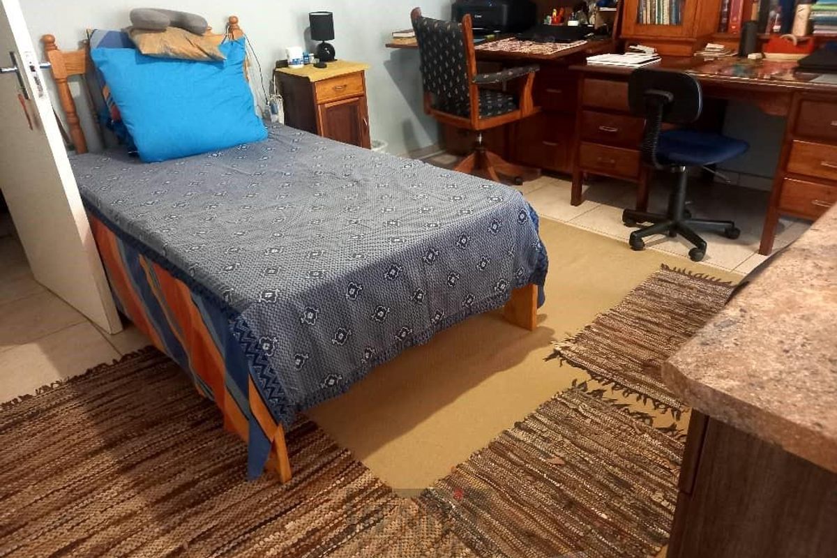 A functional bedroom space featuring tiled flooring and a built-in desk area, suitable for use as a study or sleeping quarters.