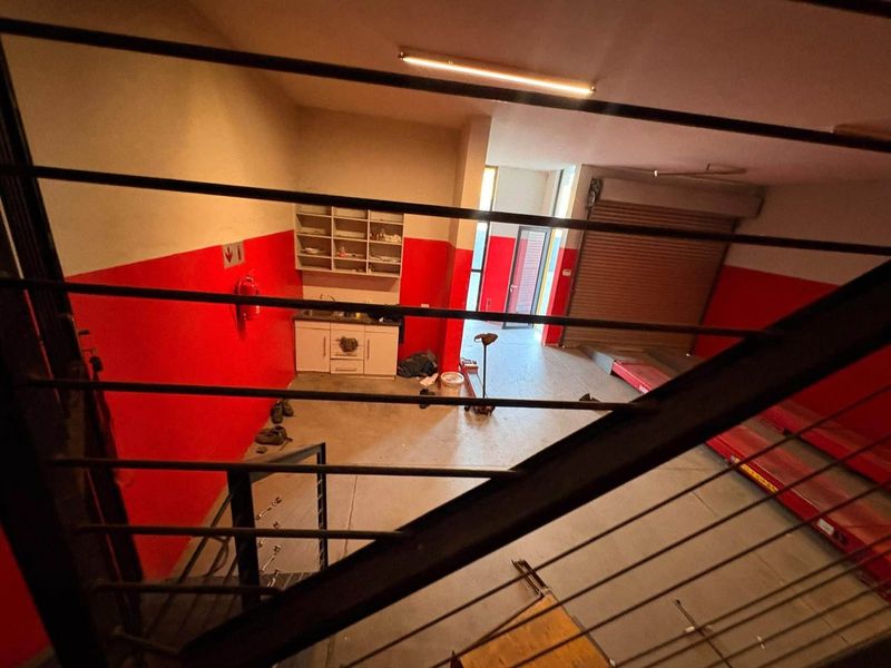 Industrial utility space featuring a roller shutter door, built-in cabinetry with a sink, and high-visibility red wall accents.