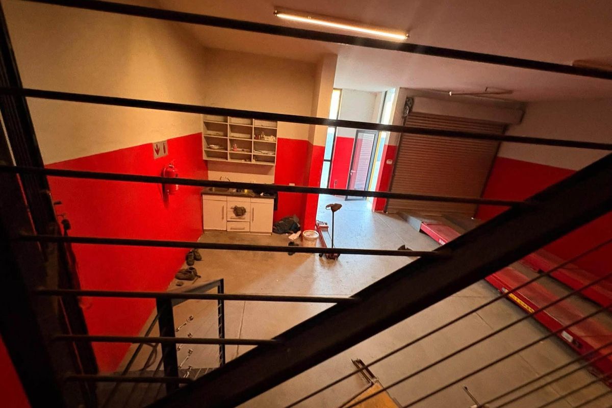 Industrial utility space featuring a roller shutter door, built-in cabinetry with a sink, and high-visibility red wall accents.