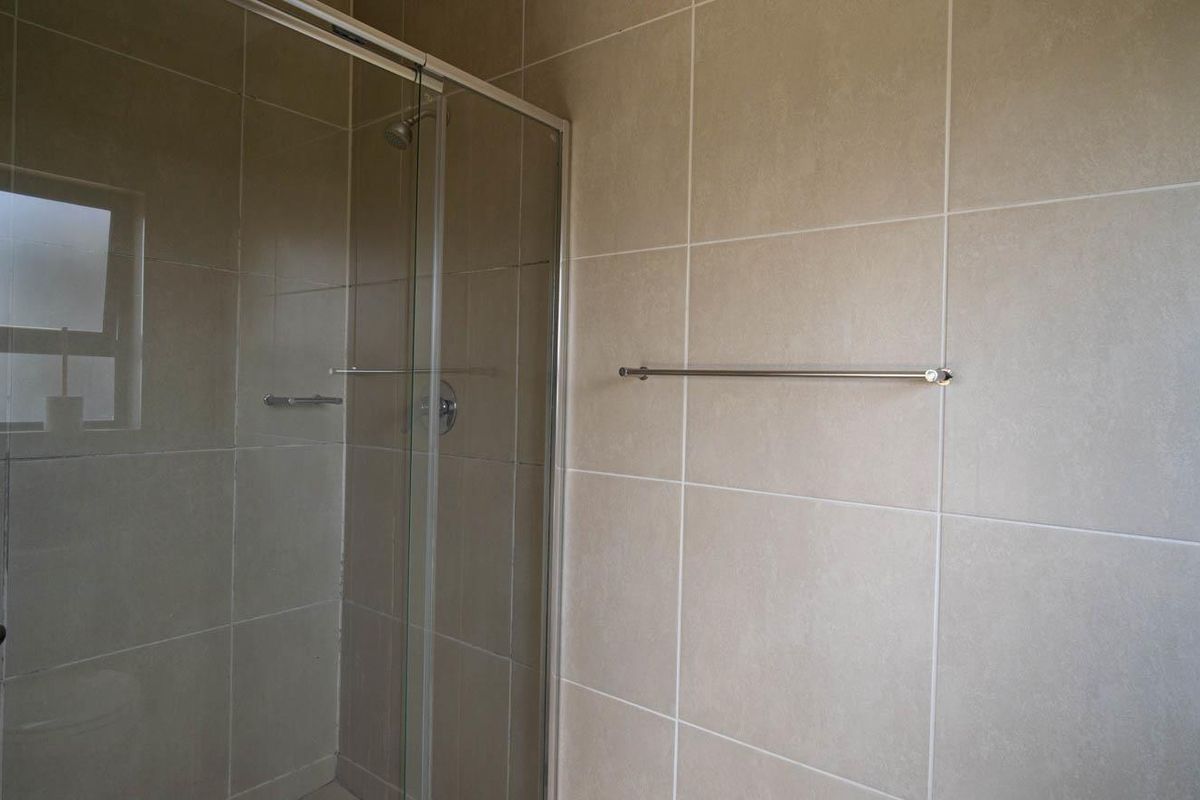 A modern bathroom featuring a glass-enclosed shower with neutral wall tiling and a fitted towel rail.