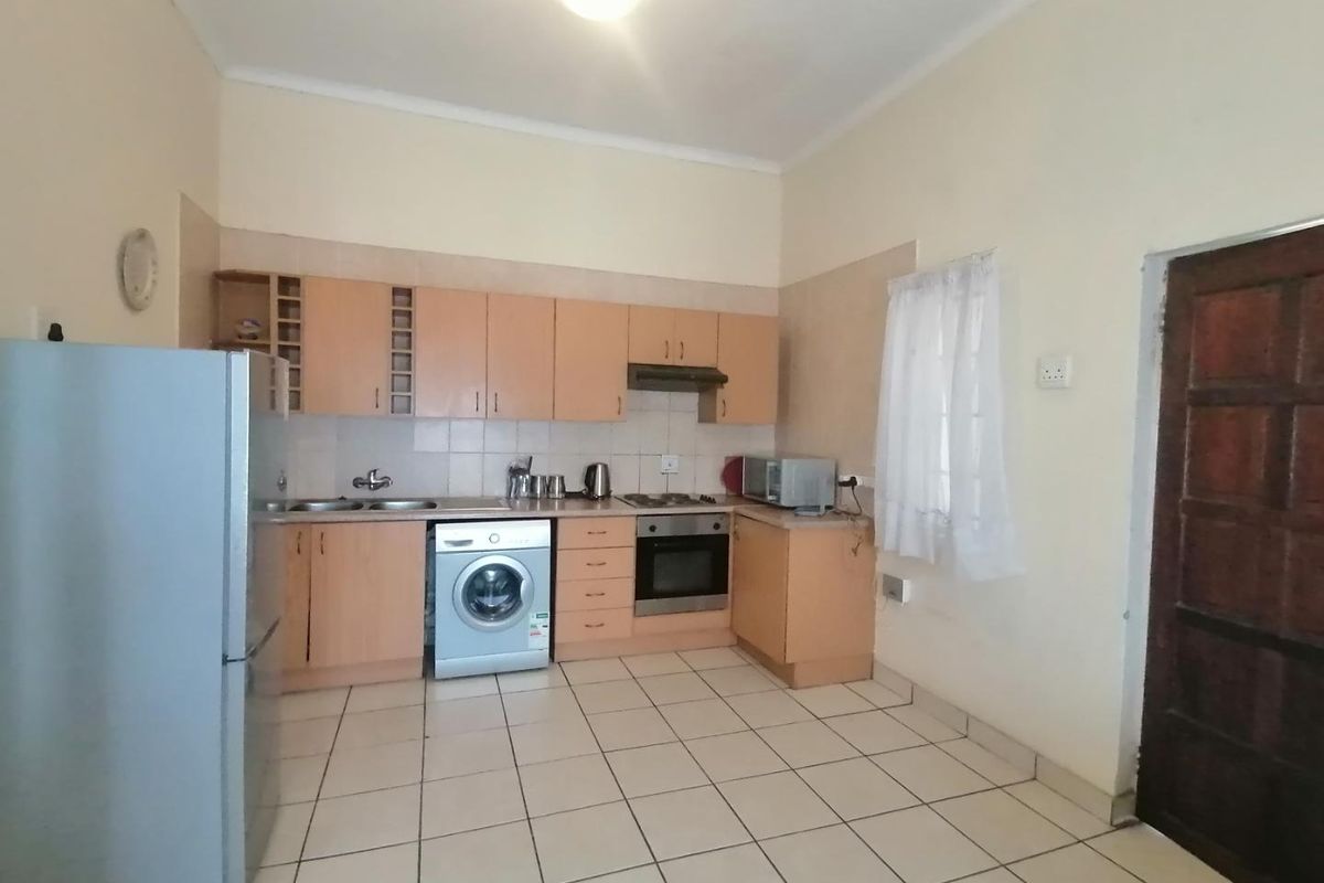 Functional kitchen featuring built-in cabinetry, integrated oven and hob, tiled splashback, and tiled flooring with direct access to the exterior.