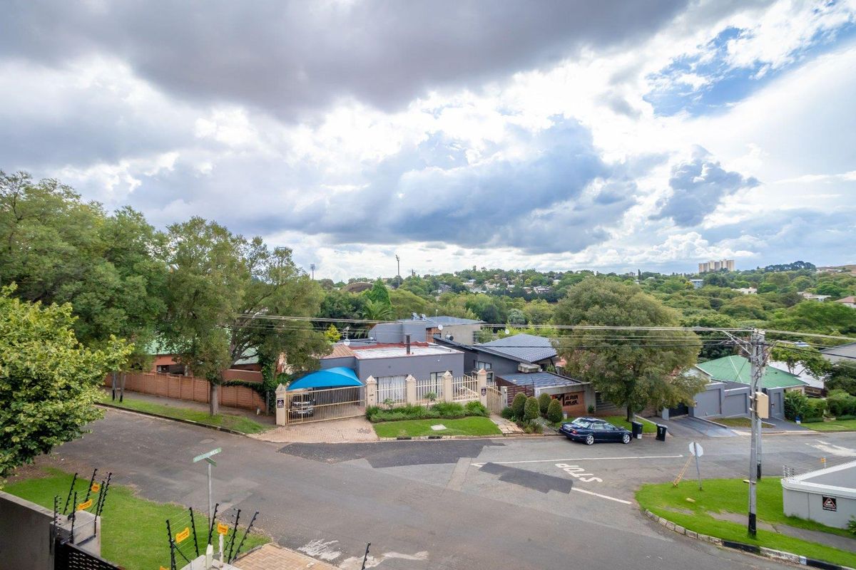 An elevated aerial view of the property showing the street-facing facade, driveway, perimeter fencing, and surrounding suburban landscape.