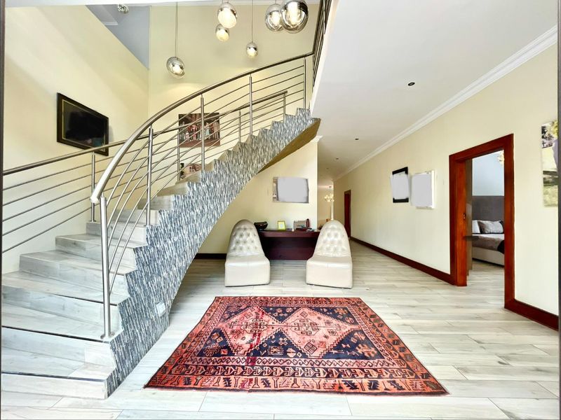 Spacious entrance hall featuring a striking curved staircase with stainless steel balustrades, decorative tiled risers, and modern recessed lighting.