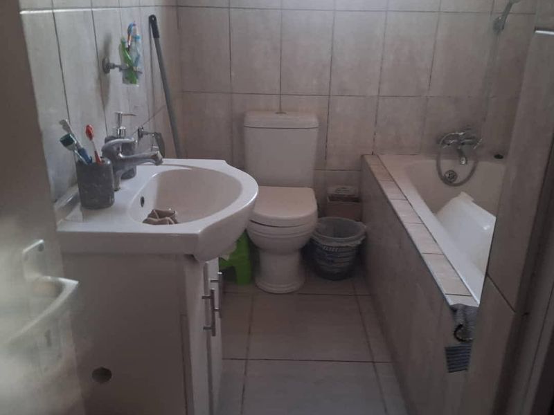 A functional bathroom featuring a vanity basin, toilet, and bathtub with tiled finishes throughout.