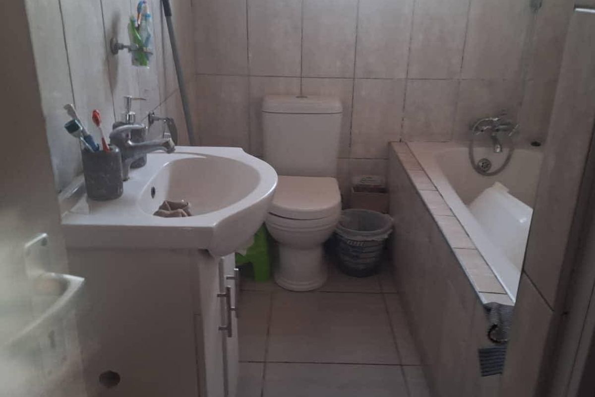 A functional bathroom featuring a vanity basin, toilet, and bathtub with tiled finishes throughout.