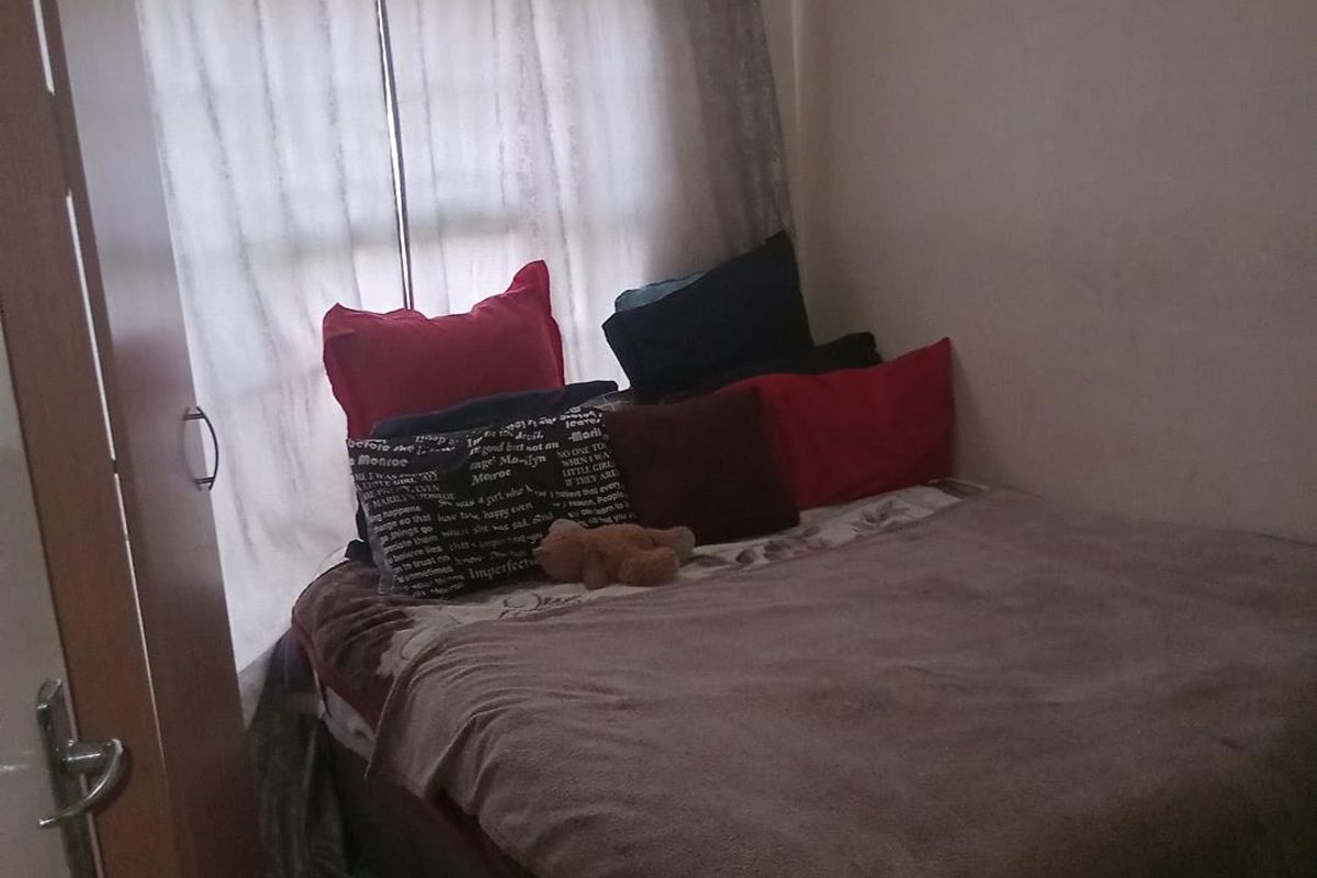 A compact bedroom featuring a window with curtains and tiled flooring.