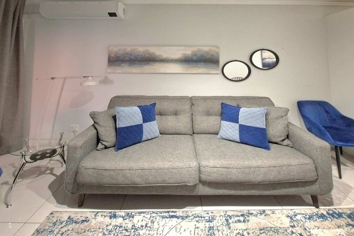 A well-maintained living room featuring tiled flooring and a wall-mounted split-system air conditioning unit.