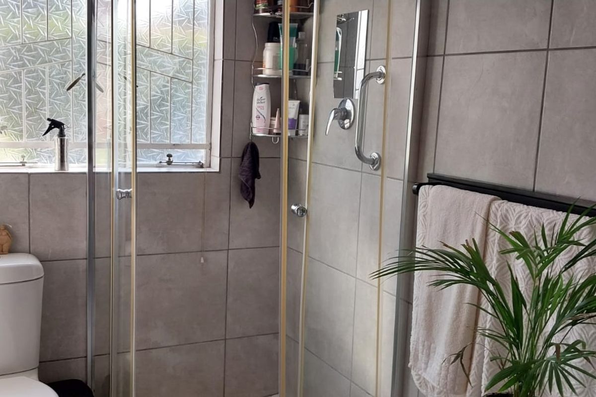 A functional bathroom featuring a tiled shower enclosure, a modern toilet, and a window with privacy glass.