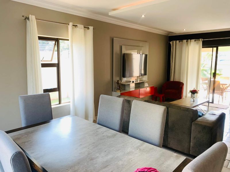 Open-plan living and dining area featuring tiled floors, recessed ceiling lighting, and large sliding glass doors providing access to the outdoor patio.