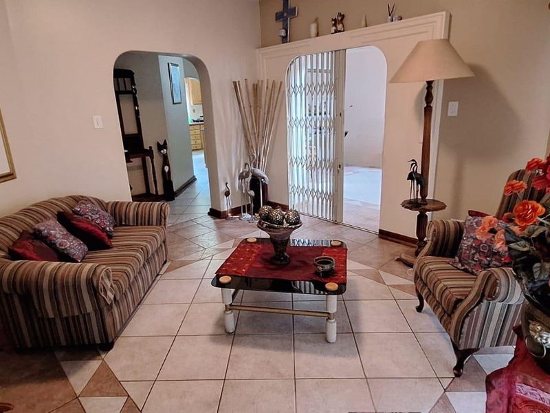 A living room featuring ceramic tile flooring and an arched doorway leading to an adjacent space with a security gate.