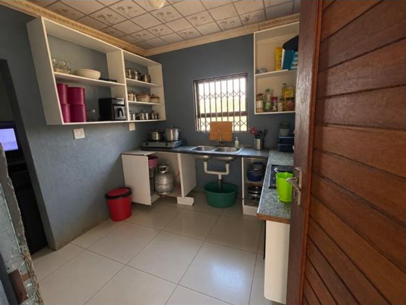 A functional kitchen featuring built-in cabinetry, tiled flooring, and a double sink, offering a practical layout with potential for modern updates.