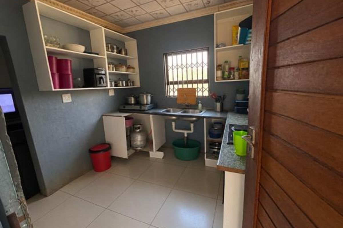 A functional kitchen featuring built-in cabinetry, tiled flooring, and a double sink, offering a practical layout with potential for modern updates.