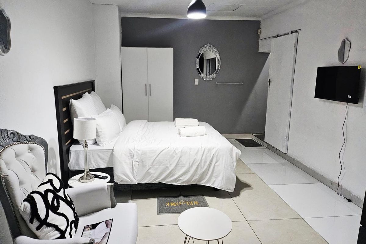 A bedroom featuring tiled flooring, a built-in wardrobe, and a neutral color palette with a dark accent wall.
