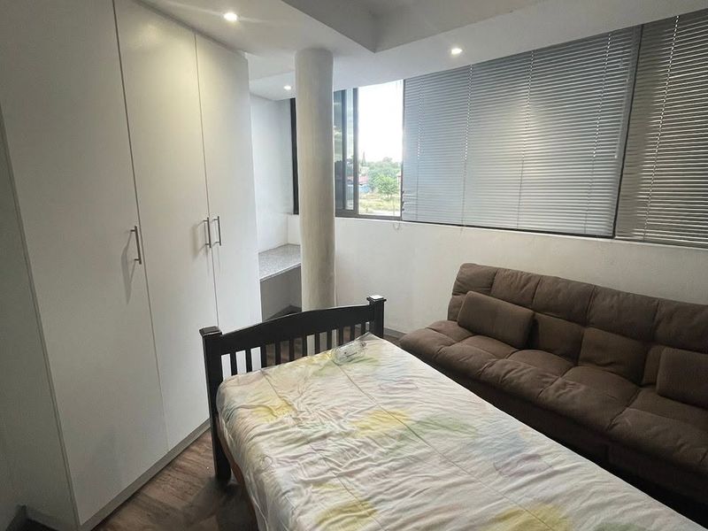 A bedroom featuring laminate flooring, built-in cupboards, recessed lighting, and venetian blinds, with a structural column and a small built-in desk area.