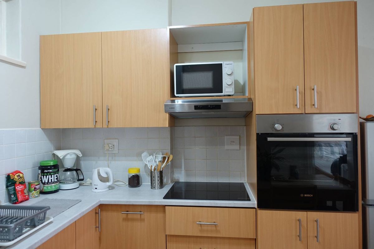 A functional kitchen featuring light wood cabinetry, a built-in Bosch oven, an electric hob, and a tiled backsplash.