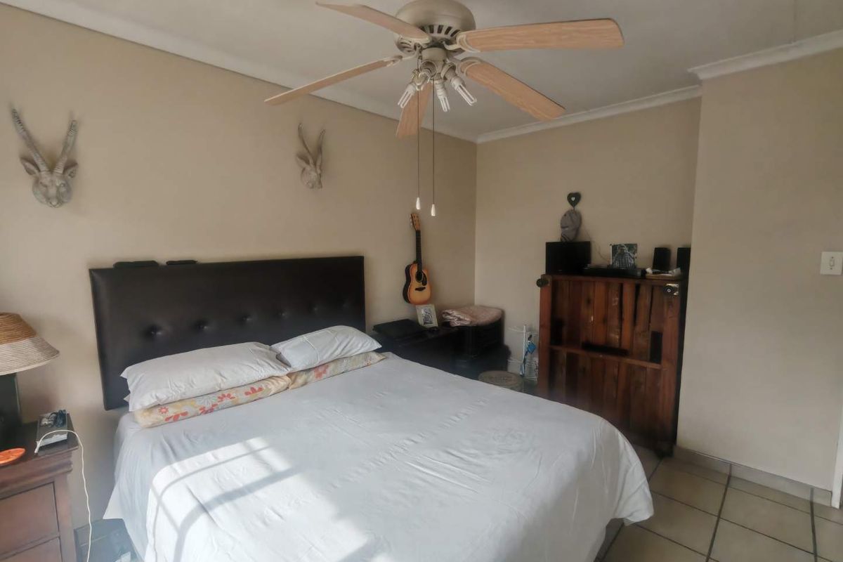 A standard bedroom featuring tiled flooring, a ceiling fan, and neutral wall tones, providing a functional and comfortable sleeping space.