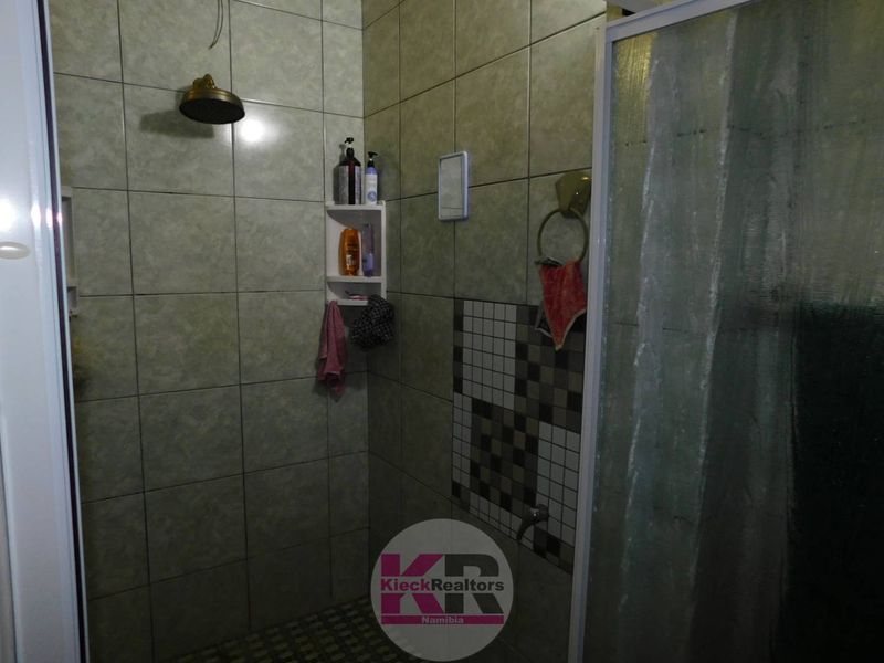 A functional shower area featuring tiled walls, a shower head, and a glass shower enclosure.